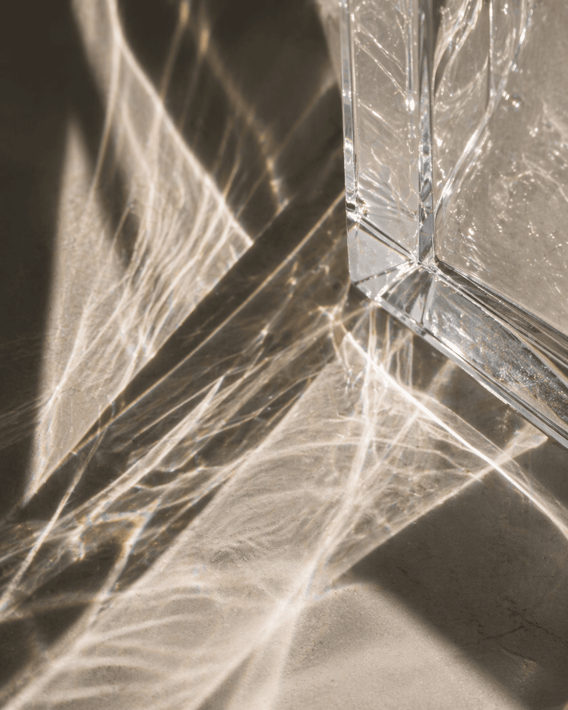 Lichtbrechung durch geschliffenes Glas auf warmem Sand